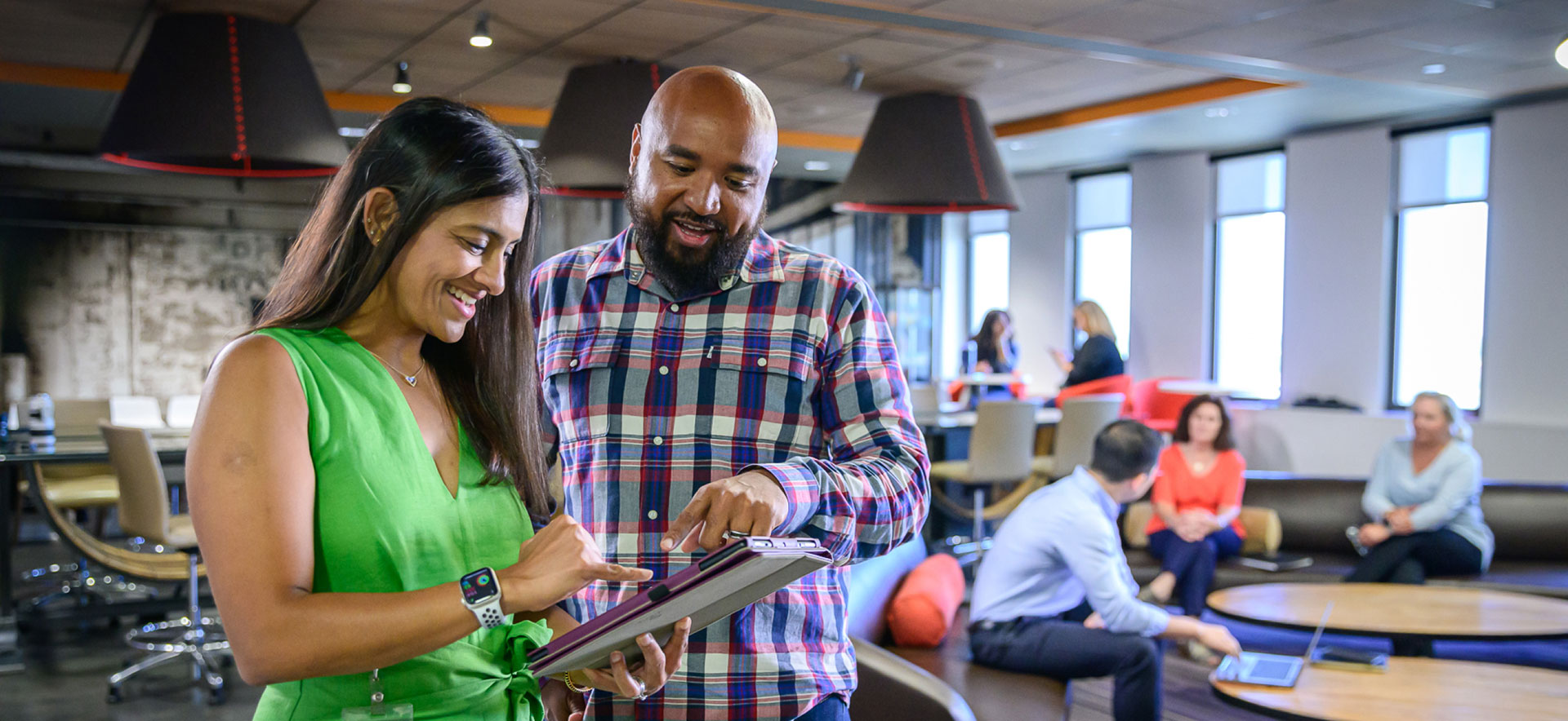a man and woman smiling looking at an iPad