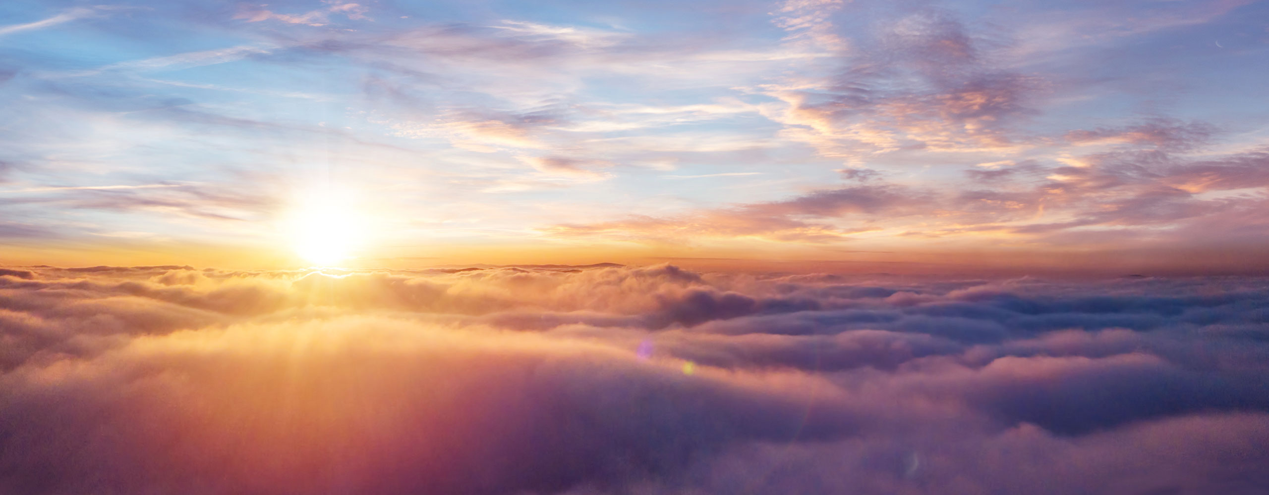Sun rising over clouds